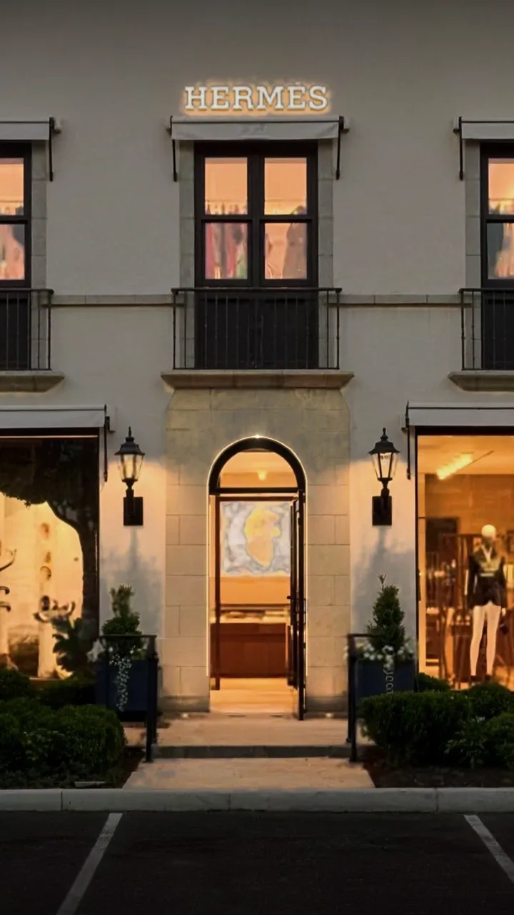 Hermès storefront entrance at blue hour, with a fine gold line tracing the arched doorway